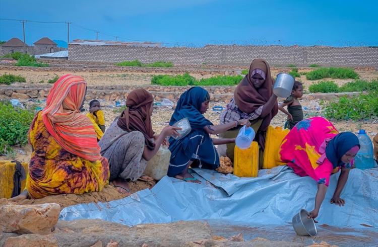 Des femmes déplacées par les conflits et les conséquences des changements climatiques en Somalie puisent de l'eau insalubre